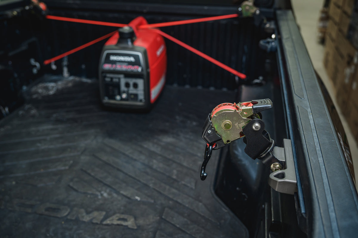 Ultimate Retractable Ratchet Strap mounted to the Toyota bed rail with a generator strapped down behind it